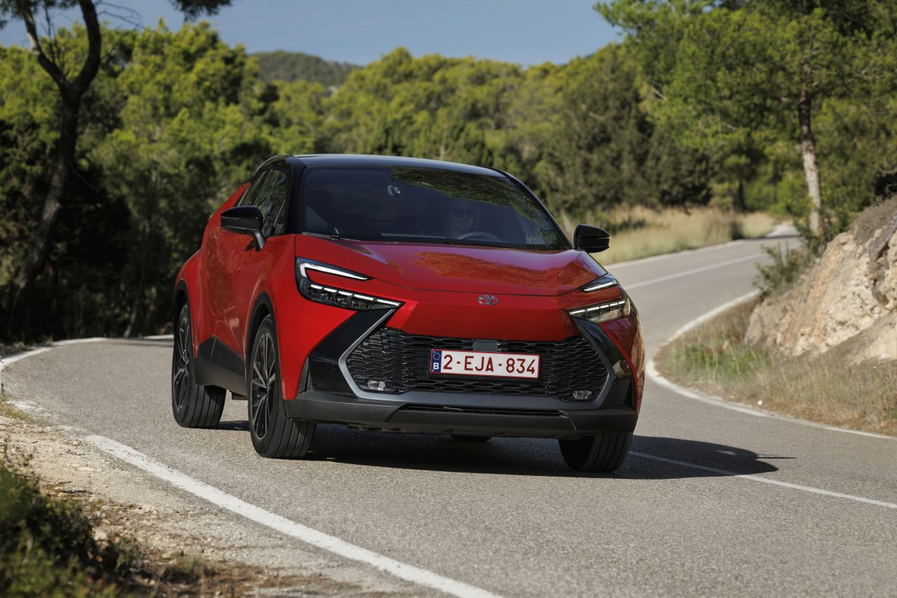 czerwona Toyota C-HR jadąca po drodze