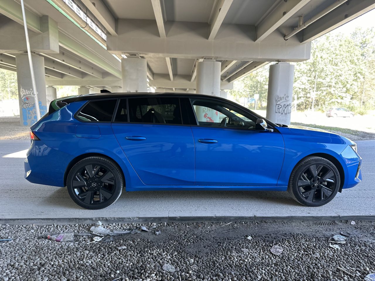 niebieski Opel Astra Sports Tourer Electric stojący pod wiaduktem